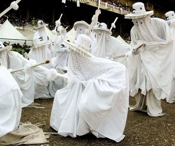 Group of people in white costumes with hats and cloaks, performing a ritual or dance Yoruba eyo culture.